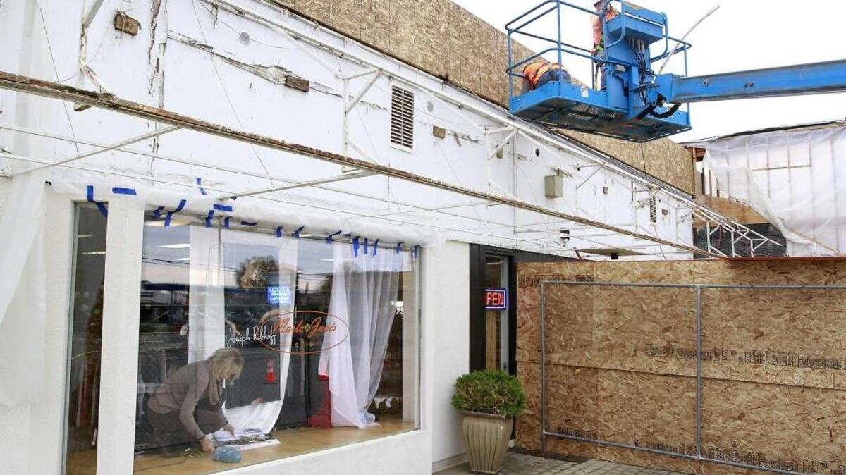 Toni Cavanaugh, an employee of Marla June’s Clothing Company, cleans the window display of the Marineland Plaza store while construction workers Jose Aguilar, left, and William Bricker work to replace the awning. The exterior of the mall at West Clearwater Avenue and Edison Street in Kennewick is being remodeled. All the businesses are still open.