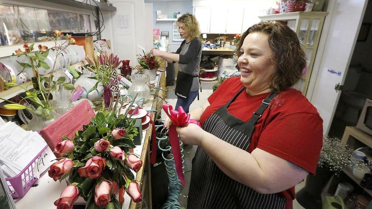 Melissa Behen, left, and Tiffanni Wright, co-owners of Lucky Flowers, share a laugh Monday morning while creating Valentine’s Day flower arrangements in their Kennewick store. Watch a video at www.tricityherald.com/video