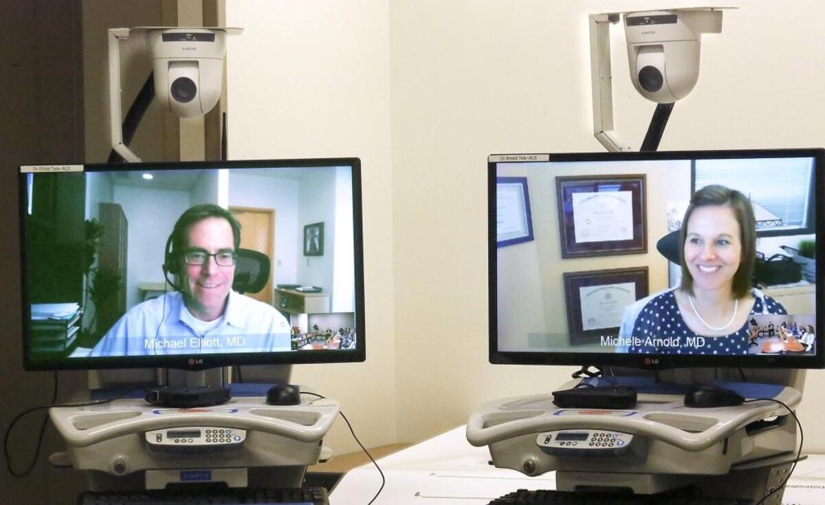 Dr. Michael Elliott, left, and Dr. Michele Arnold of the Swedish Neuroscience Institute in Seattle hold a video-conference with a team of multidisciplinary health care professionals at the Kadlec ALS Clinic in the Healthplex facility on Lee Boulevard in Richland. Watch a video at: www.tricityherald.com/video