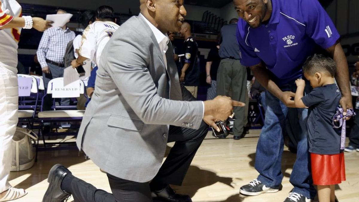 Anthony Davis, former Pasco High School football player and NFL retiree, bends down to say hello to Leon Wright-Jackson and his son Leon Jr., 2 years old, during a celebration at the Pasco gym. Davis was honored and the school received a golden football in his name along with Ron Howard as Pasco graduates who played in Super Bowl games. See more photos at www.tricityherald.com.