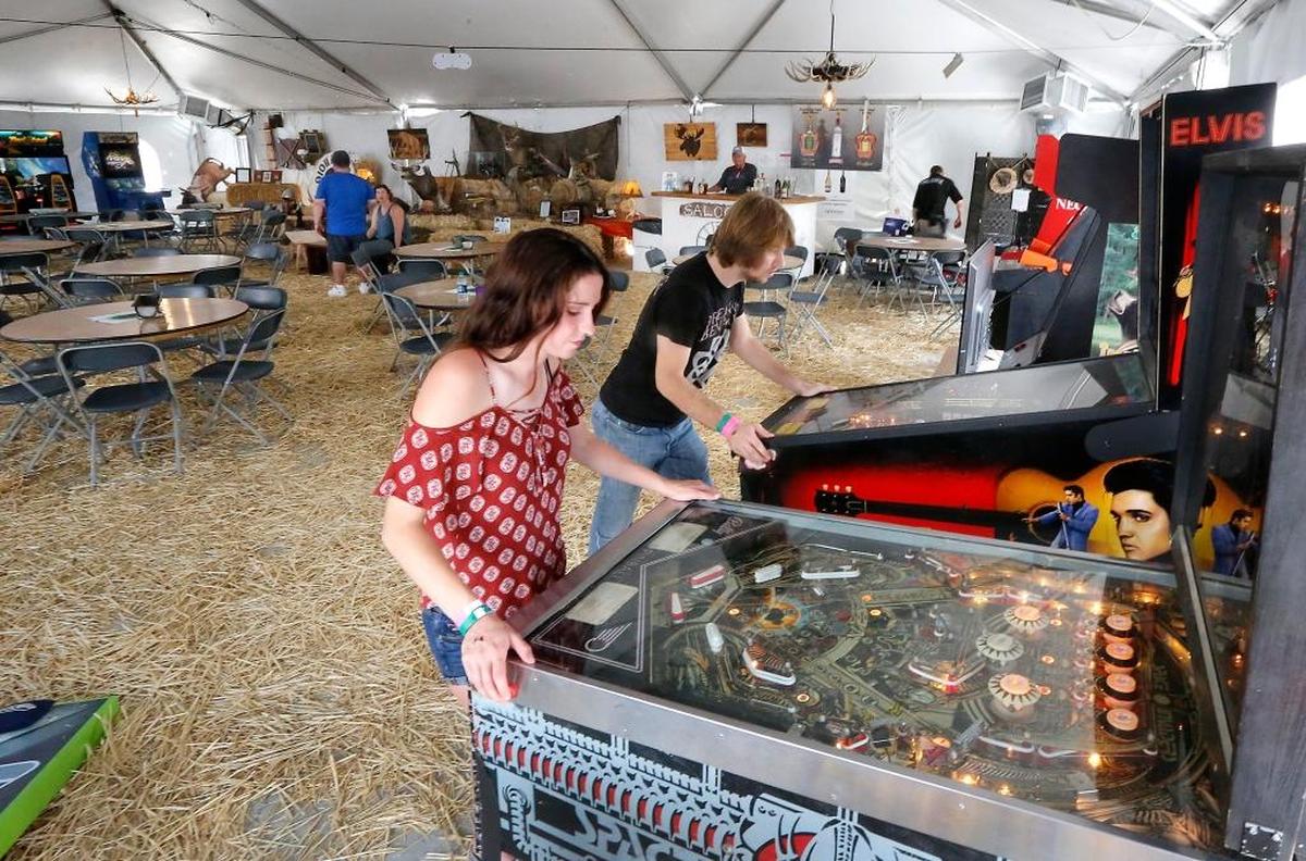 Katelyn Garrity, left, and Cole Sherman, both of Kennewick, try out some of the pinball games featured in the new Big Game Room at the Benton Franklin County Fair & Rodeo. The adults-only venue is near the food court and features air-conditioning and seating. There are free arcade games, a jukebox, cell phone charging station and a full bar inside the tent area. Watch a video at tricityherald.com/video
