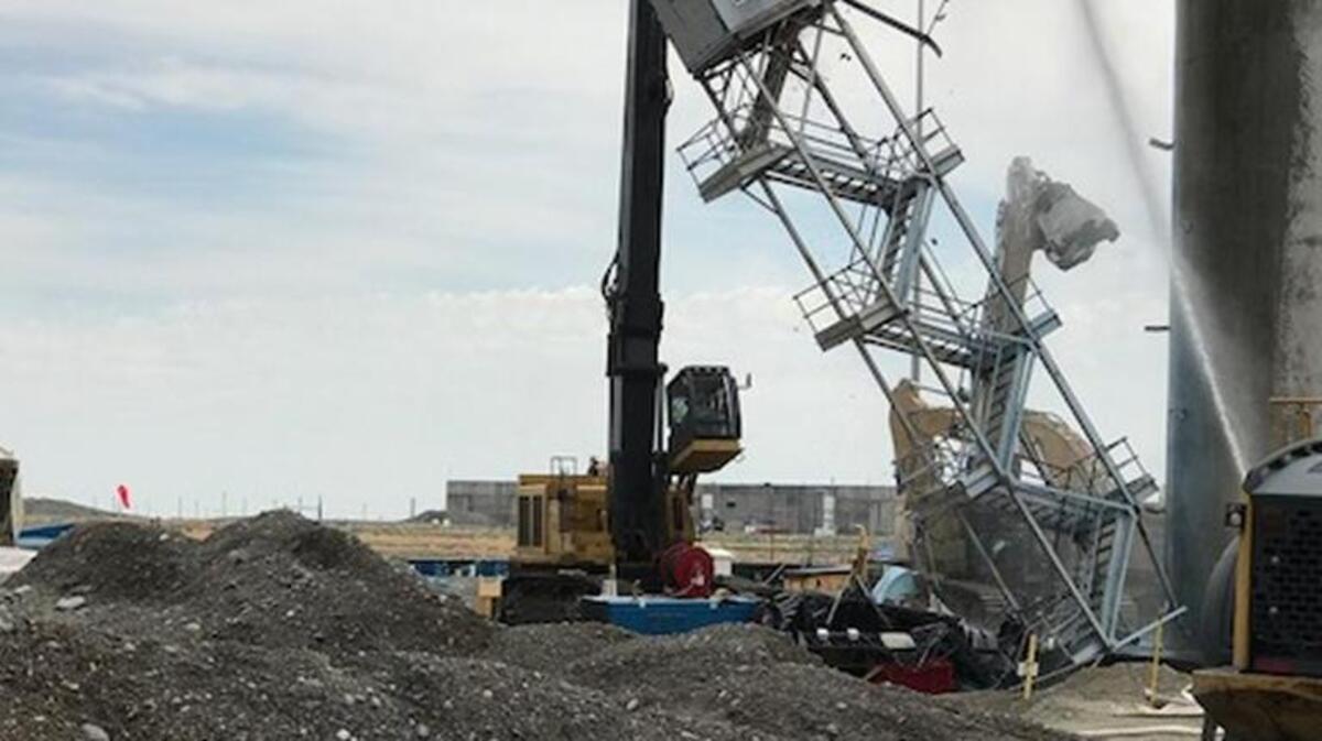 Heavy equipment is used to pull the sample shack away from the ventilation stack at Hanford’s Plutonium Finishing Plant. The shack was used during Hanford’s production years to take air samples from the stack, which will be demolished using explosives on July 15.