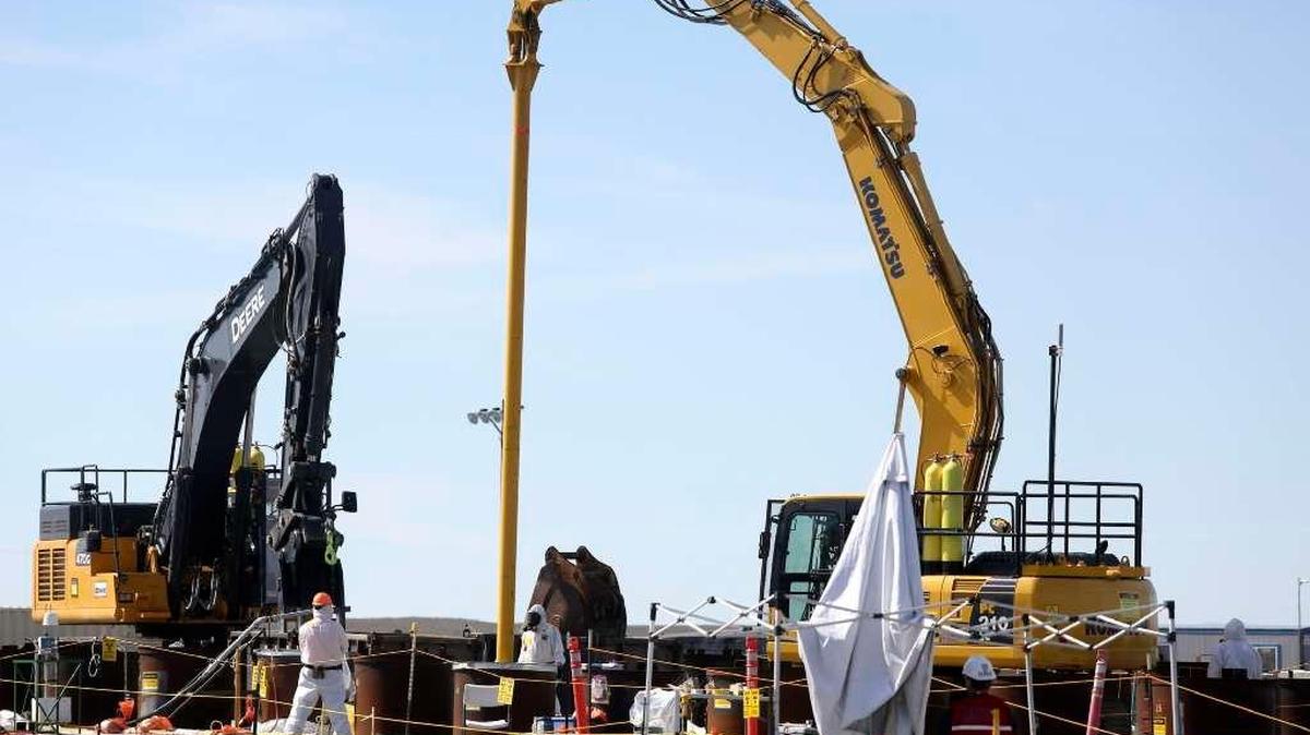 A clamshell shovel is lowered out of view inside an underground overcasing after an auger was used to chew through waste and the walls of a vertically buried pipe at the Hanford 618-10 Burial Ground north of Richland.