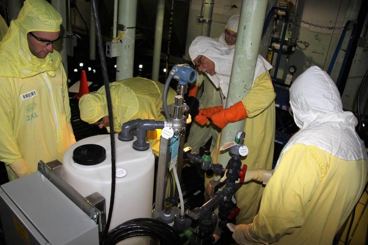 Workers check equipment inside the K West Basin at the Hanford nuclear reservation. The equipment was used to remove radioactive sludge for transfer to central Hanford storage.