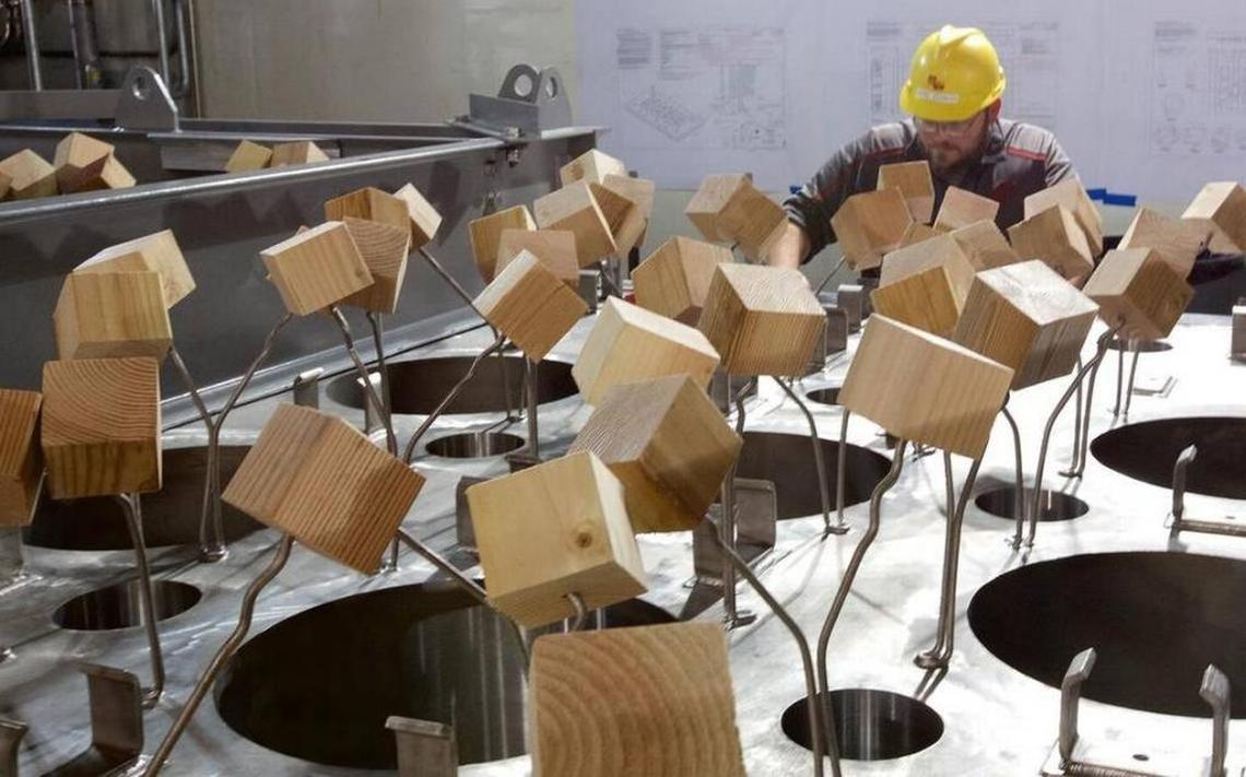 Hanford vitrification plant workers place wooden 4-by-4-inch blocks over steel rods as protection while they finish work on the glass-melter lids.