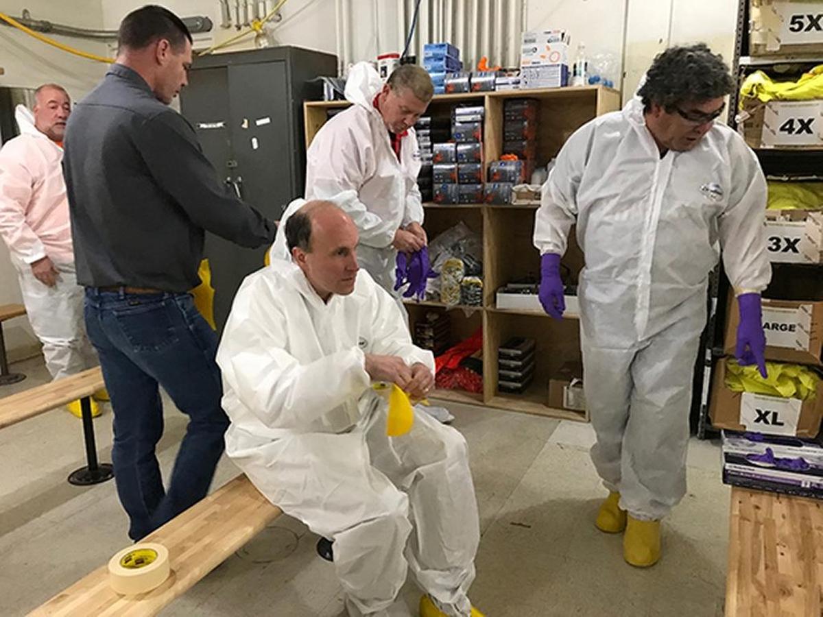 Paul Dabbar, center, the Department of Energy undersecretary for science, puts on protective clothing to enter the air lock of the 324 Building just north of Richland near the Columbia River.