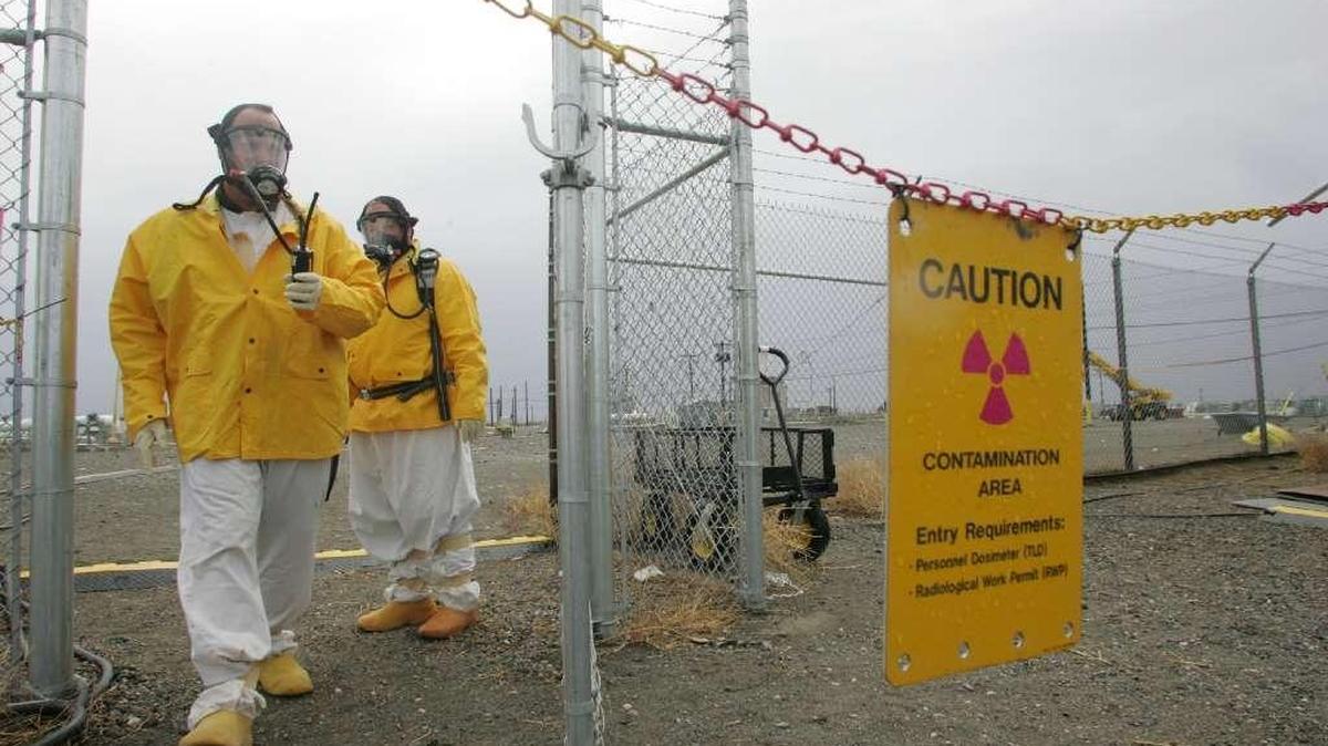 Workers leave a Hanford tank farm wearing supplied air respirators to protect them from chemical vapors associated with waste in the underground waste storage tanks.