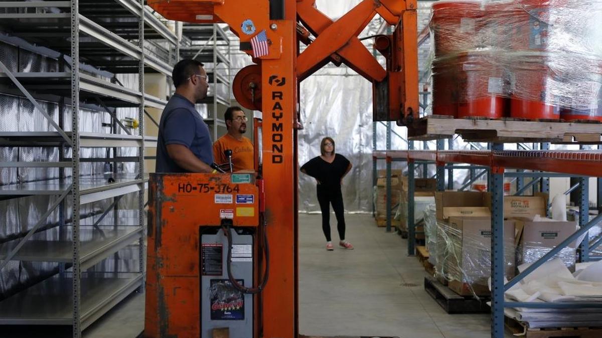 Jillian Gardner-Andrews, project coordinator with the Hanford History Project, looks on as Alex Cuello from Mission Support Alliance, moves containers filled with artifacts. Thousands of Hanford artifacts are being moved into Richland where they can be put on public display. See a video at tricityherald.com/video.