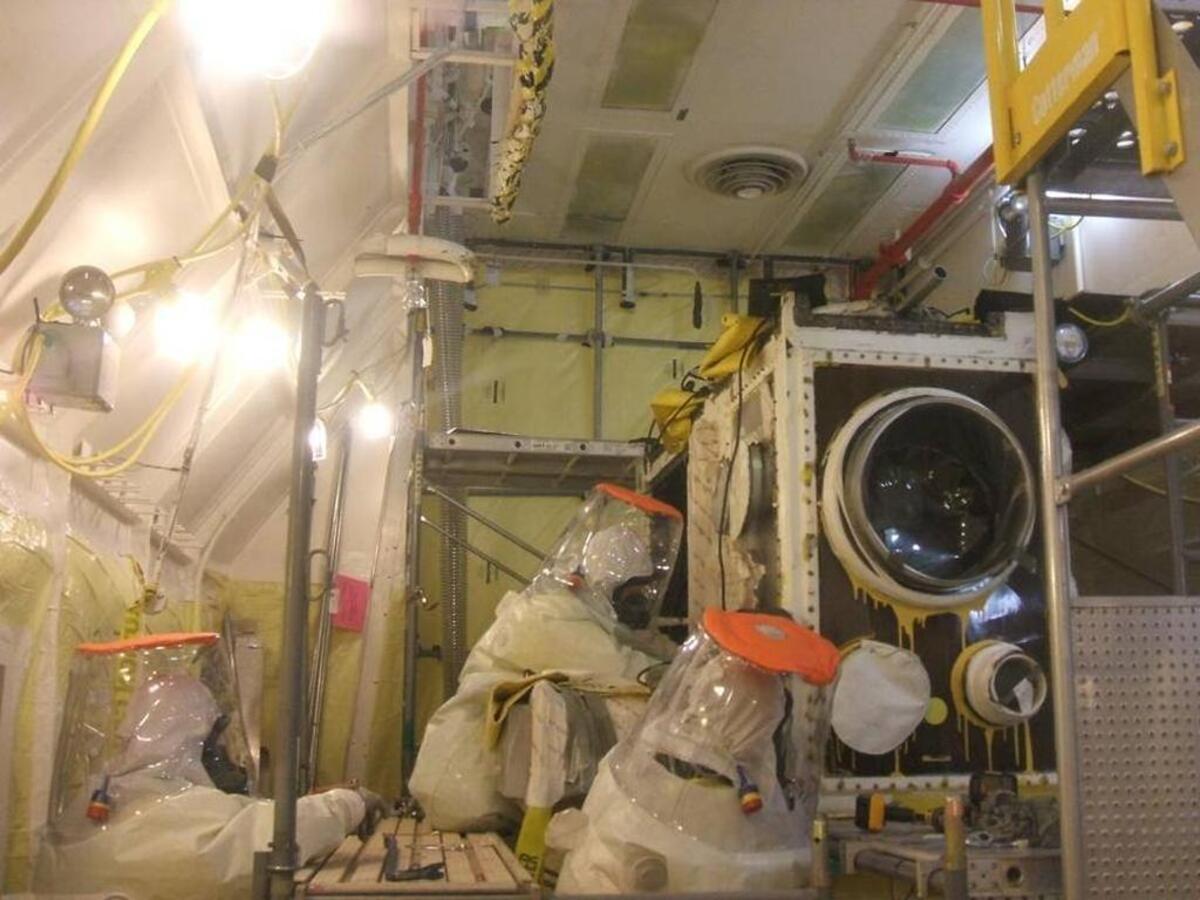 CH2M Hill Plateau Remediation Co. workers in protective clothing work to remove highly contaminated equipment in preparation for the demolition of the Plutonium Finishing Plant.