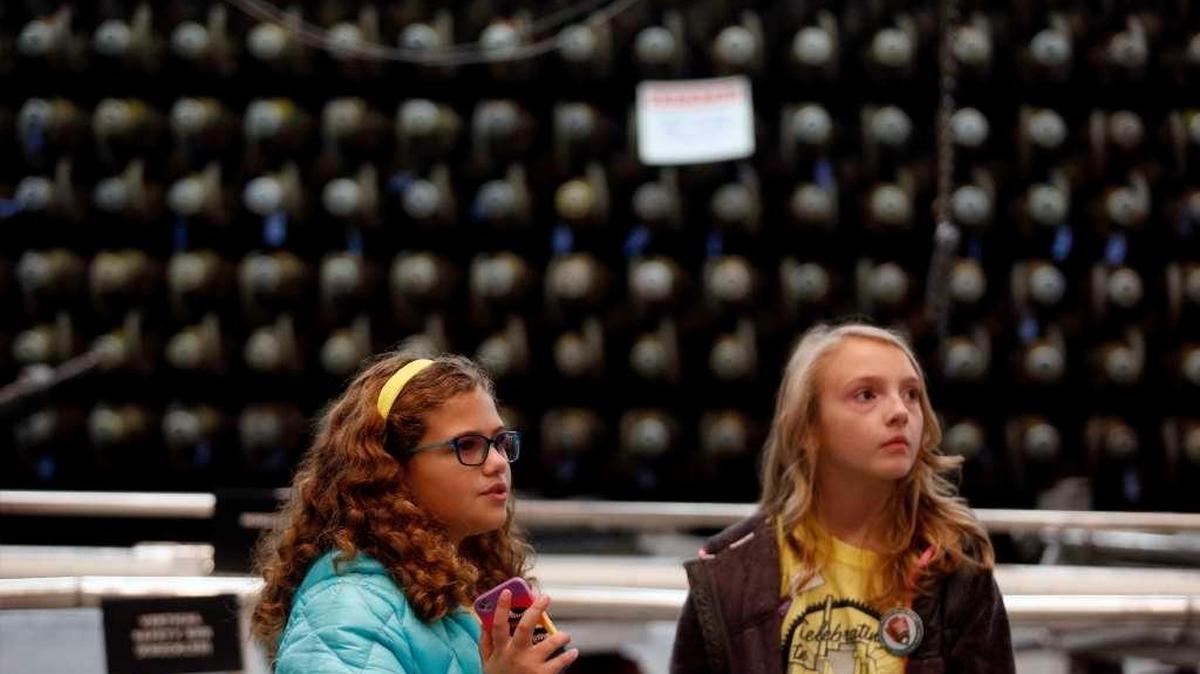 Kassidy Lewis, right, and Sophia Maiuri, both fourth-graders at White Bluffs Elementary School, stand in front of the face of the B Reactor during a tour in November. More tours for school classes are planned with the lifting of age restrictions for visiting B Reactor.