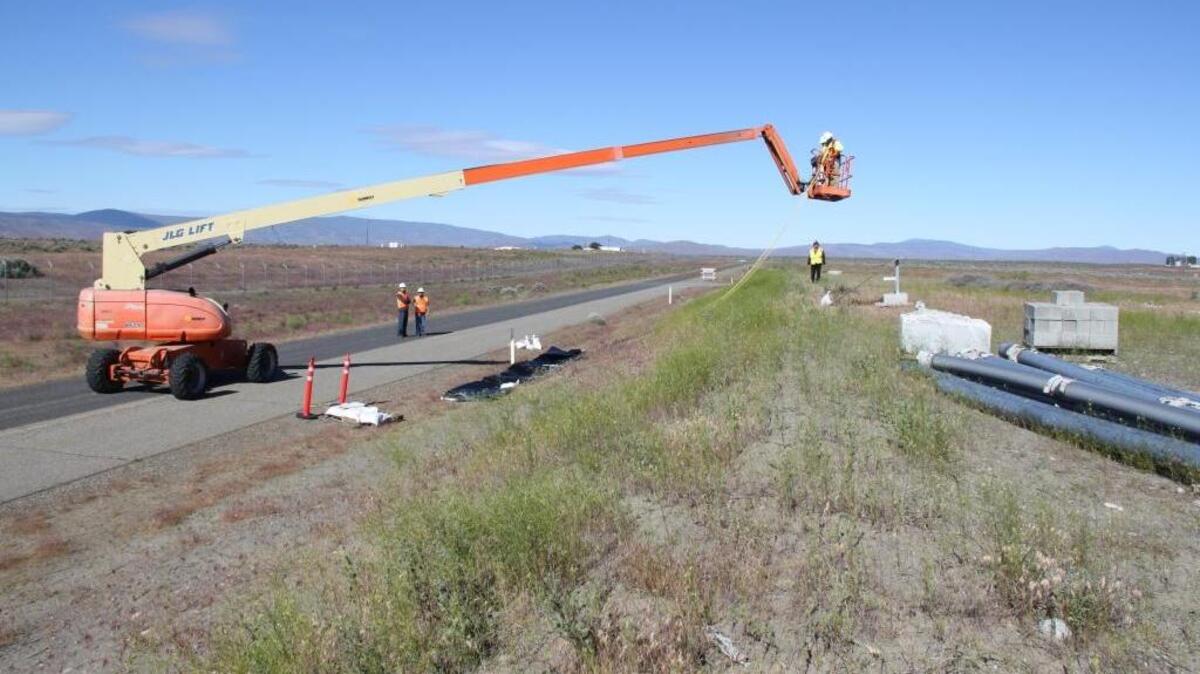 Hanford workers practice the method that will be used for covering a breached waste tunnel with heavy plastic.