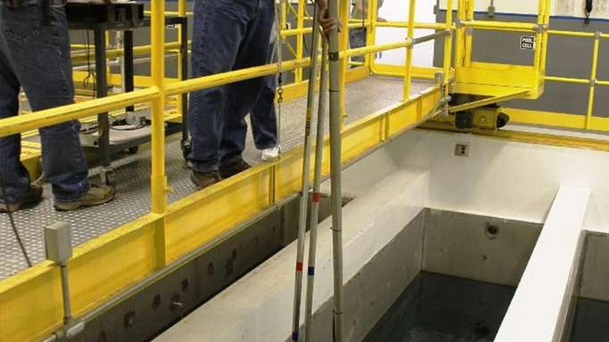 Hanford workers inside the Waste Encapsulation Storage Facility use long-handled tools to rearrange highly radioactive capsules at the bottom of a water-filled pool to distribute heat generated by the cesium and strontium in the capsules.