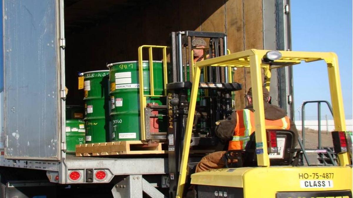 Drums containing a mix of low-level radioactive and hazardous chemical waste are loaded into a truck at the Hanford nuclear reservation.