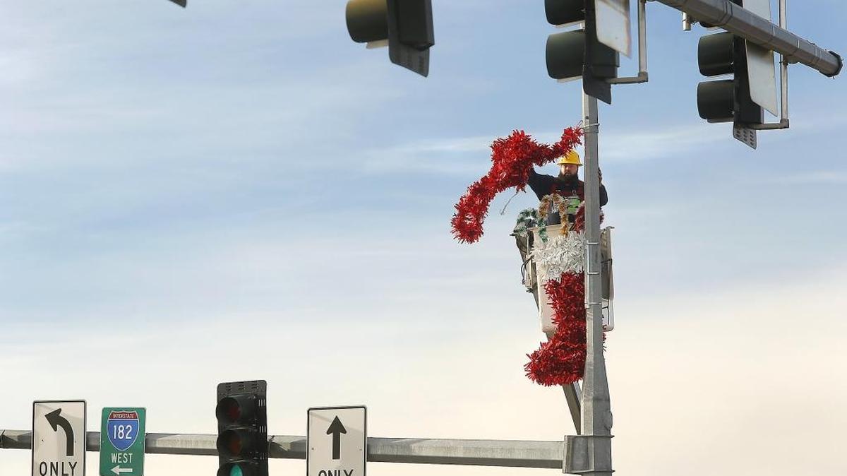 Kyle Runyon, a Pasco city employee, unfurls red garland Monday while hanging Christmas decorations on a street light pole at the intersection of Road 68 and Burden Boulevard in Pasco. Runyon and a co-worker have been busy decorating each corner of at about 14 intersections in downtown and west Pasco.