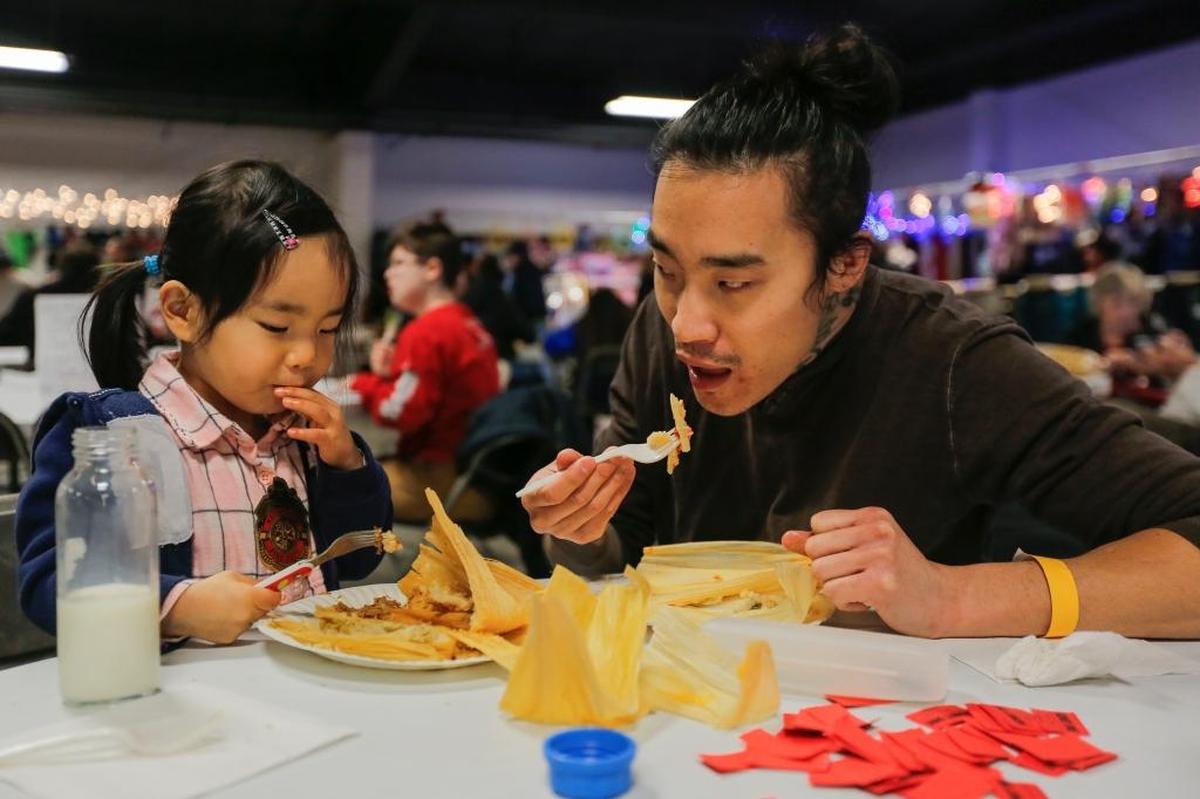 Ryan Clark eats tamales with his 3-year-old daughter Jin-Ah. Along with the tasty traditional food, the event also had crafts, vendors, music and other performances.