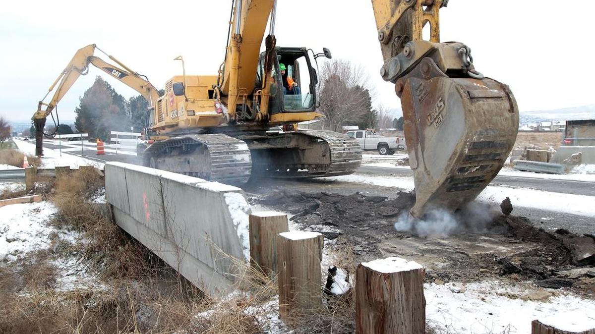Rotschy Inc. employee Dan Pratt uses an excavator bucket to scrape off a layer of asphalt Monday from the concrete bridge over a Franklin County Irrigation District canal bridge on Road 100 in Pasco. The stretch of busy city street from just south of Chapel Hill Boulevard to Argent Road is scheduled closed until Jan. 22 for the bridge removal project. The section of open canal is being replaced by an underground 48-inch supply line. Detours are in place for motorists during the closure.
