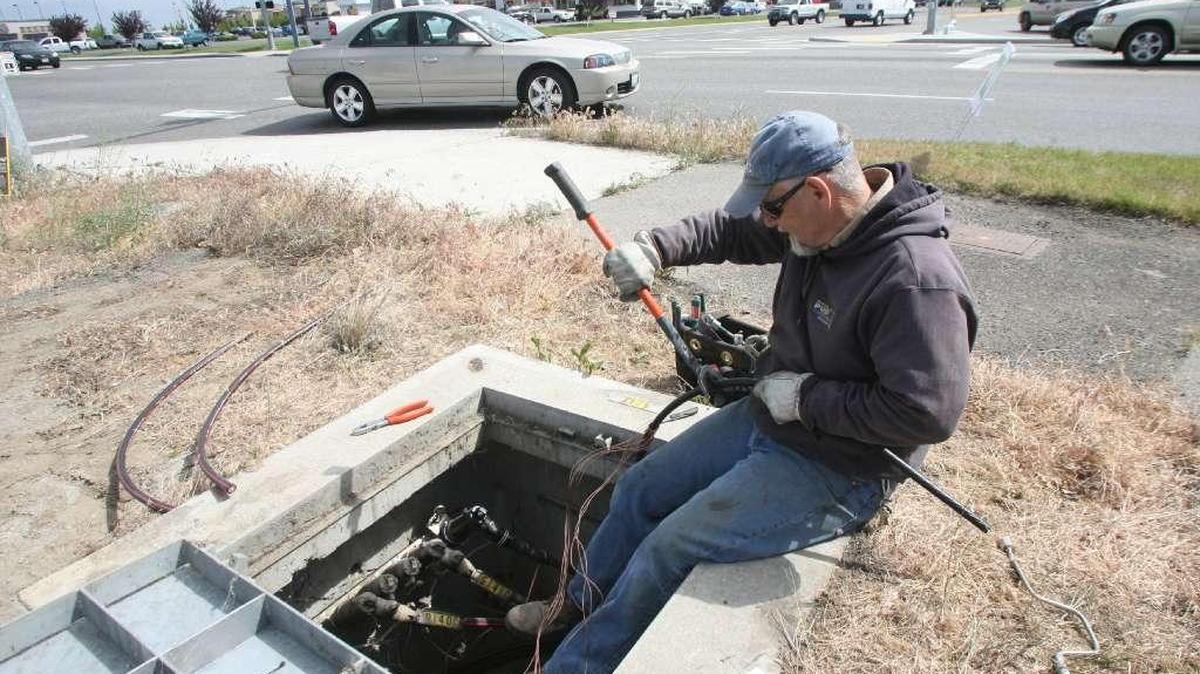 A Franklin PUD employee works on a traffic light power line in a junction vault at the corner of Road 68 and Burden Boulevard in Pasco.