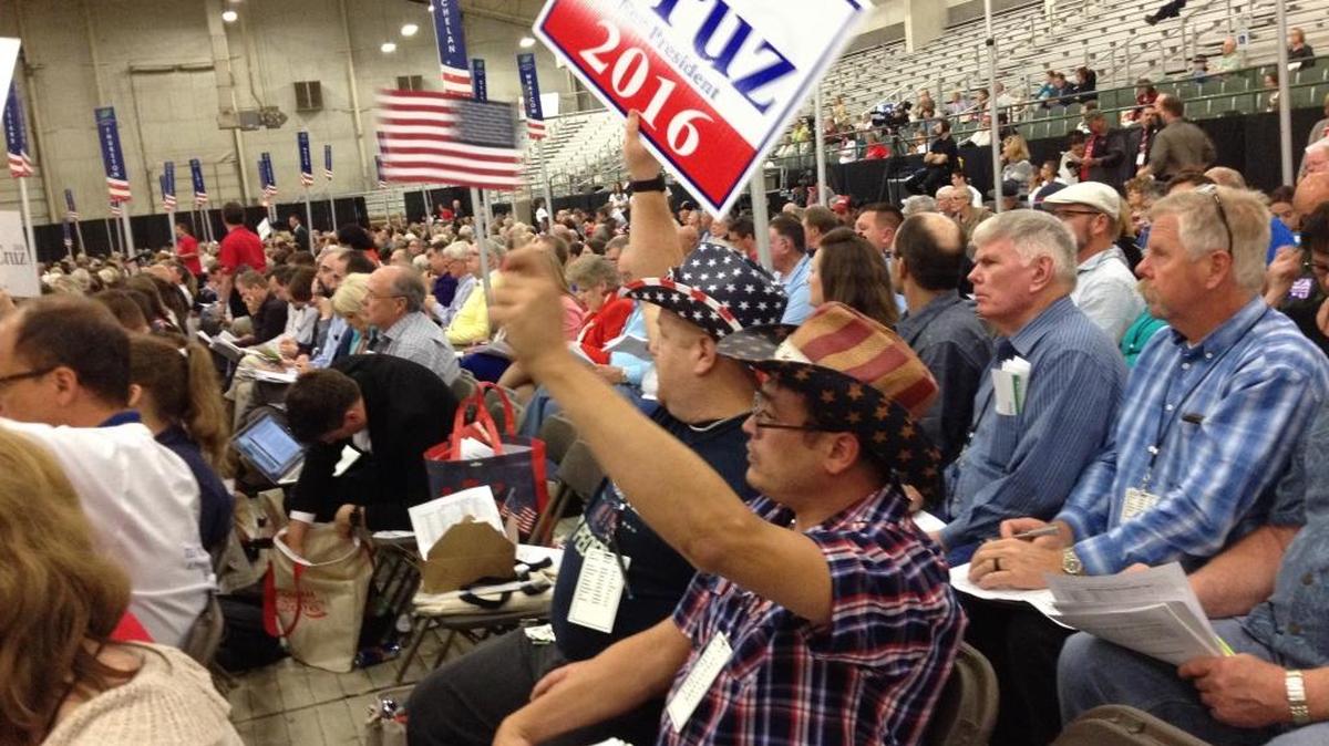 Steven Wilson holds up a Cruz sign and Adam Maldonado waves an American flag Saturday at the state Republican convention in Pasco. Both are from King County.