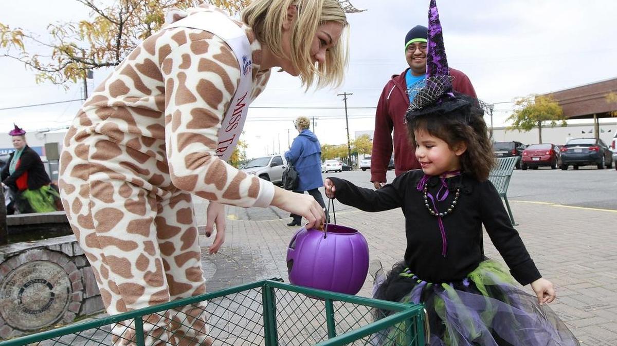 Annessa Hernandez, 4, gets pieces of candy placed in her purple plastic pumpkin Monday from Miss Tri-Cities Tayler Plunkett during the Trick or Treat Bash sponsored by the Historic Downtown Kennewick Partnership. Angel Hernandez of Richland accompanied his daughter to the annual Halloween event held in downtown Kennewick. Watch a video at tricityherald.com/video