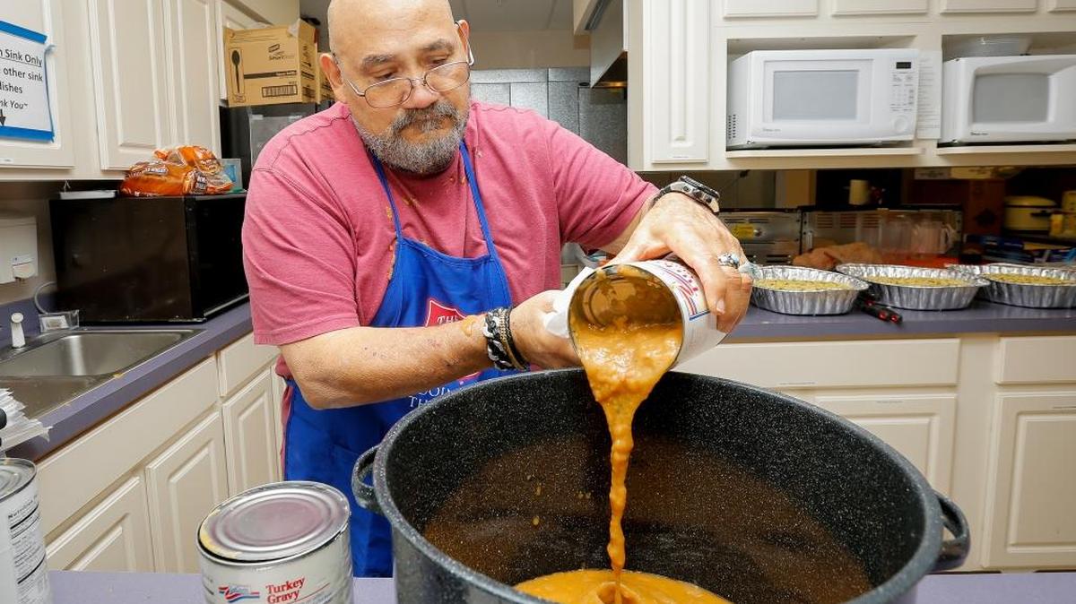 Harry Ramos, a volunteer, pours a can of gravy into a pot as he prepares food on Wednesday at the Salvation Army in Richland for Thanksgiving. Ramos has made 12 turkeys and is preparing food for up to 300 people.