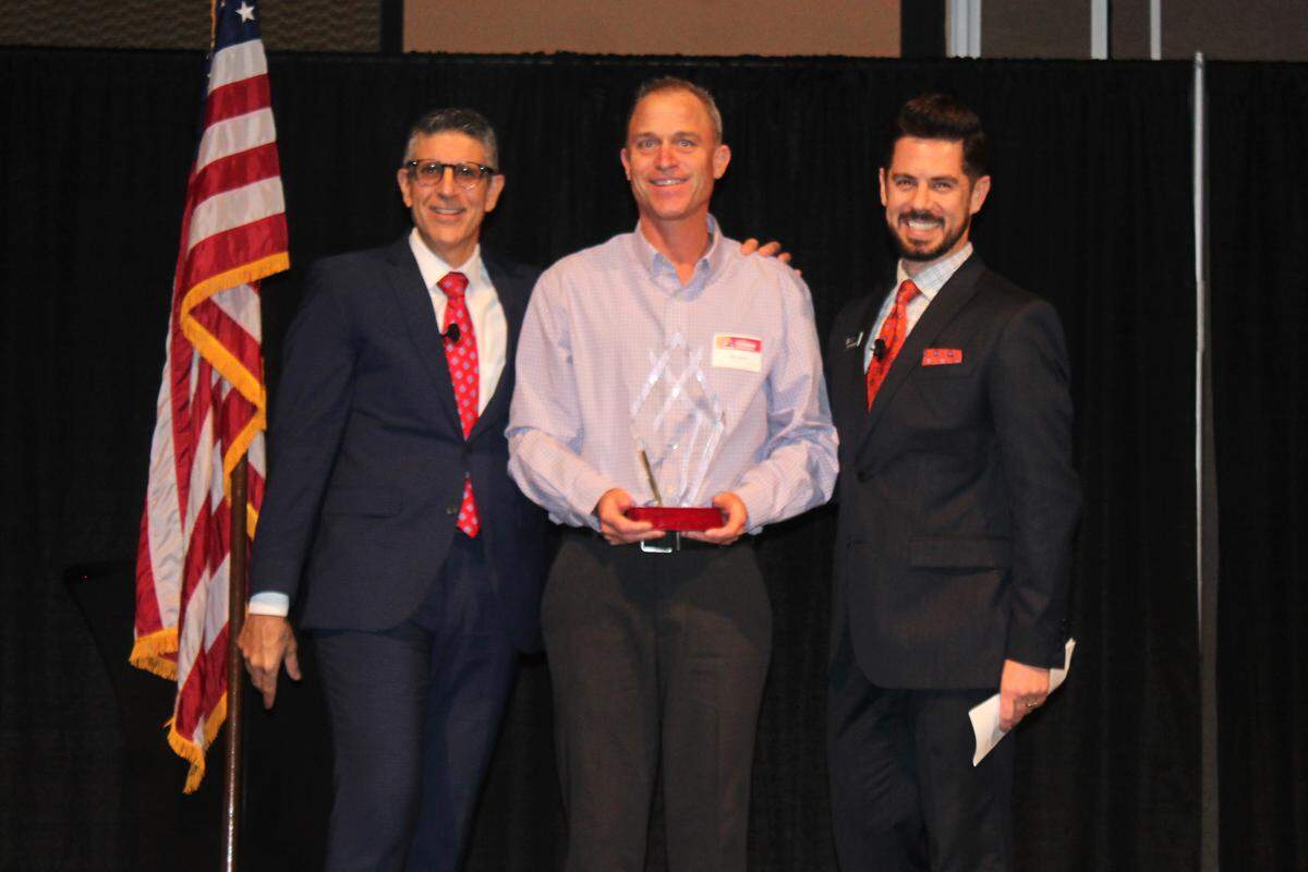 Steve Jensen, state director for the national Softball Association of Washington, center, is presented the Visit Tri-Cities 2018 Kris Watkins Tourism Champion Award, by Michael Novakovich, left, of Visit Tri-Cities, and Rob Roxburgh of Washington River Protection Services.