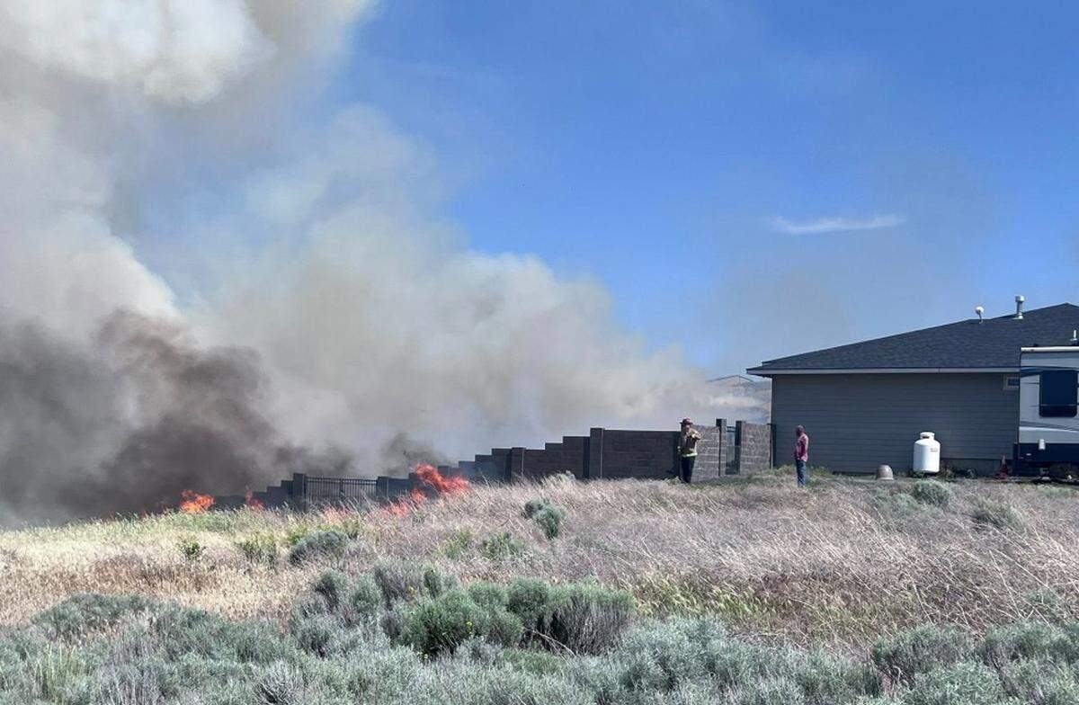 Firefighters try to protect homes from approaching flames from the Country Meadows Fire in Badger Canyon on Saturday.