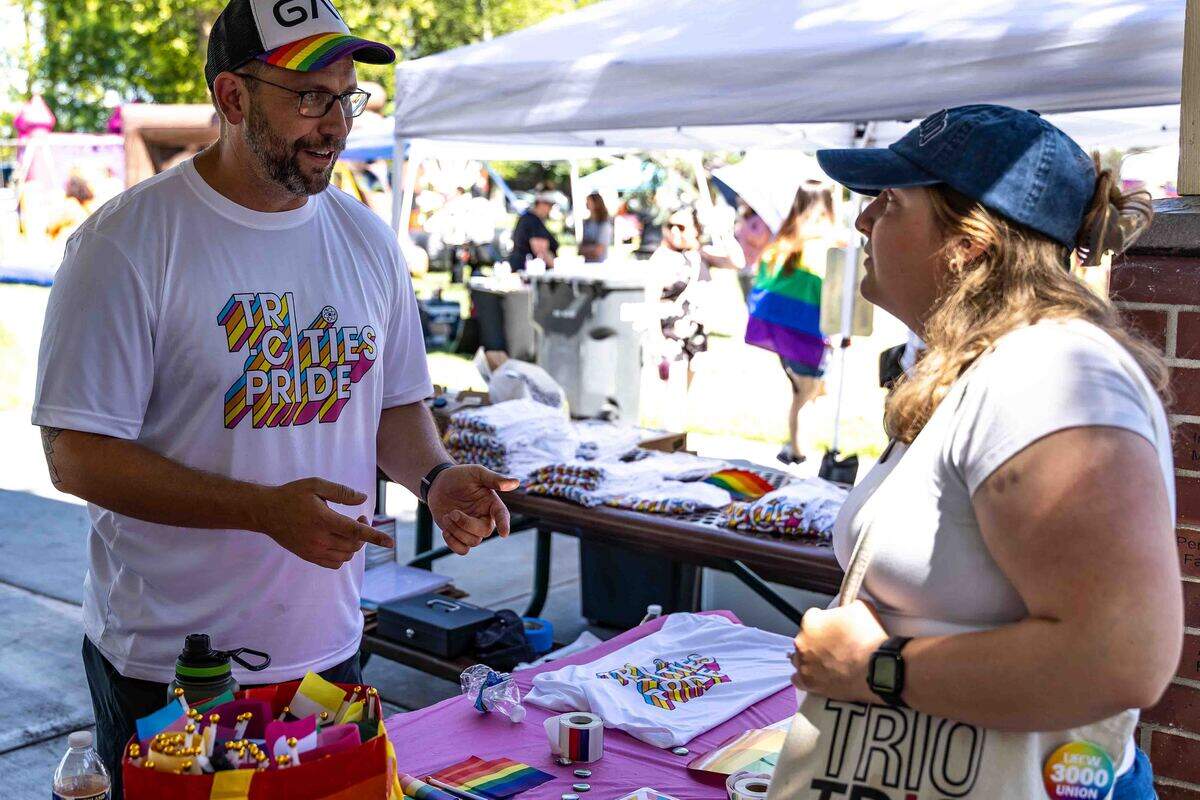 Dr. Ryan Nell, left, treasurer of the Tri-Cities Pride board of directors, talks with Caterina Amsler of Richland at an information booth during the Tri-Cities Pride Festival on June 14.