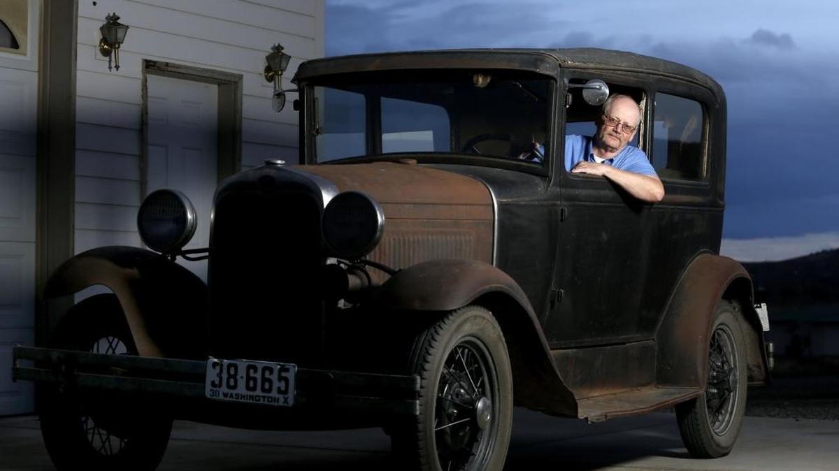 Tom Eldhardt poses for a photo this week in his 1930 Model A Tudor at the shop where he works on cars outside his home in West Richland. Eldhardt, who has refurbished several classic cars, is featured along with his Ford in the December issue of Hemmings Classic Car.