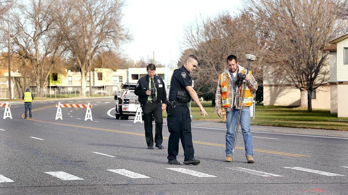 November 8, 2018 - Richland police Officer Eric Edwards with the traffic safety unit works with city of Richland surveyor Tom Boshart on Wednesday at the intersection where two boys, 9, and 12, were hit by a car Tuesday night. Detective Damon Jansen follows behind taking photos of the scene on Jadwin Avenue at Wilson Street.