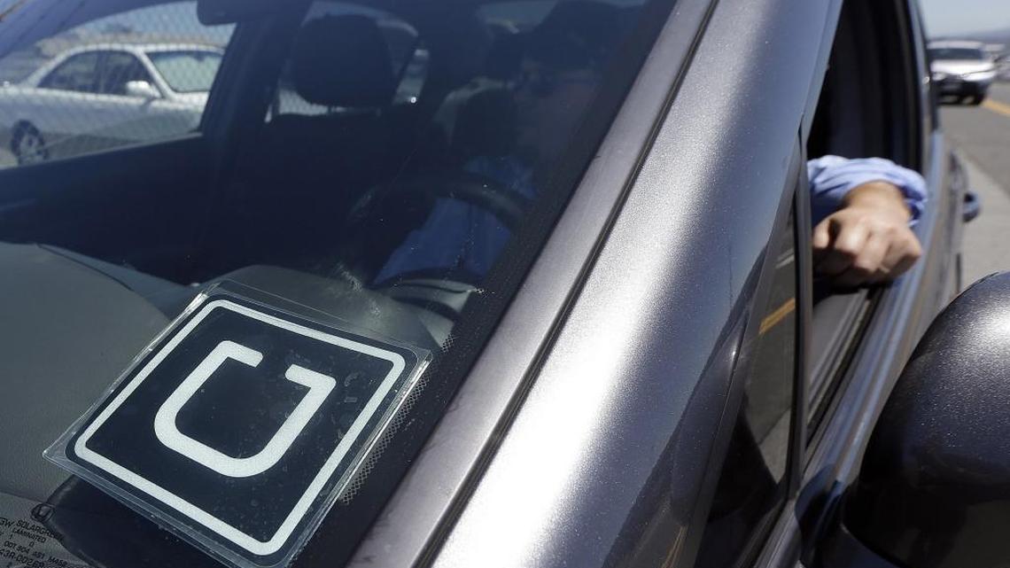 A discrete sticker in a windshield denotes a Uber vehicle parked near the San Francisco International Airport. Uber is in discussions with the city of Kennewick, but the two sides are stuck on who should perform driver background checks.