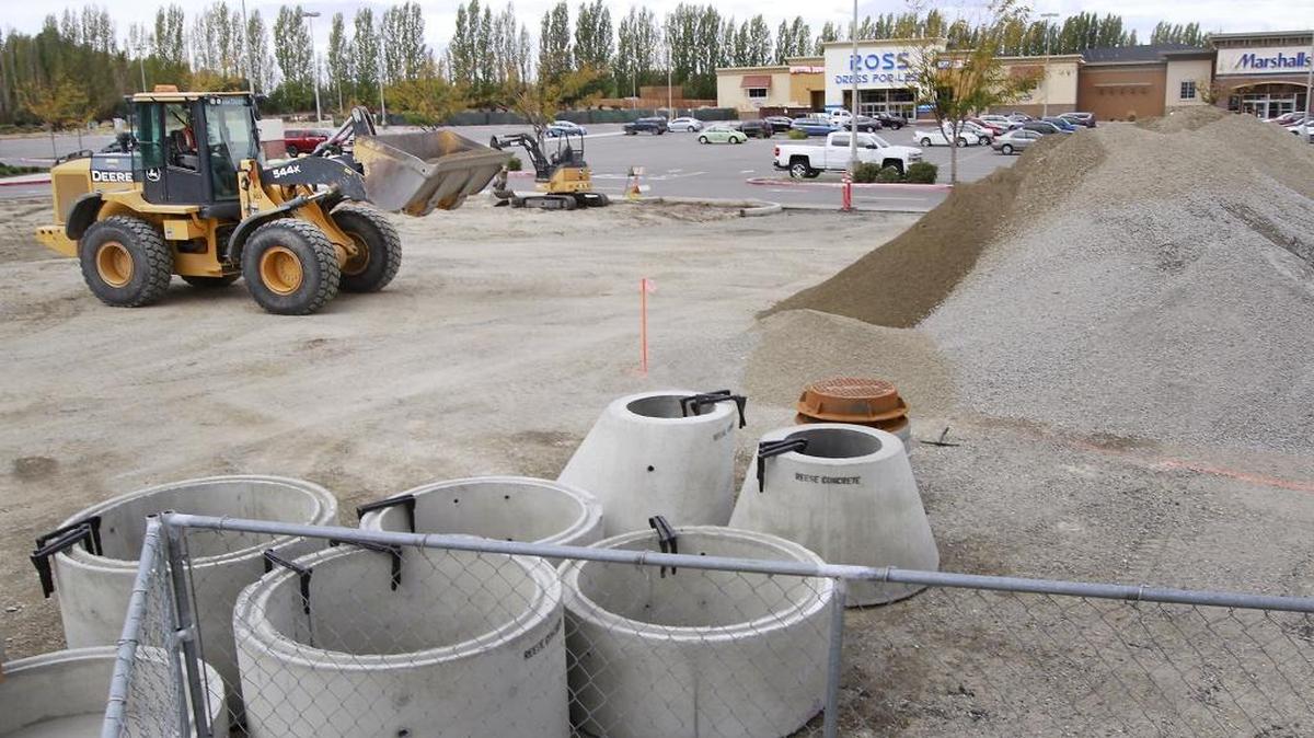 A front-end loader moves gravel Wednesday at a pad site at the Vintner Square retail development on Queensgate in Richland.