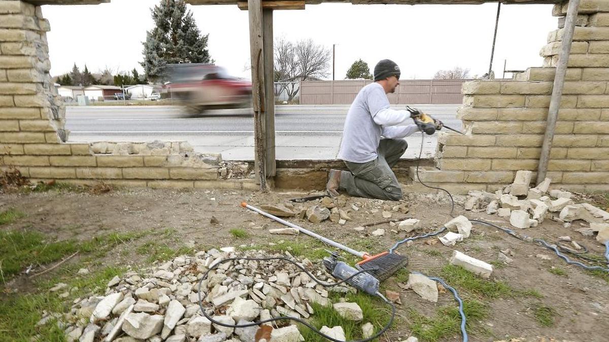 Craig Woodall, an employee of Cliff Thorn Construction, removes bricks Monday from a damaged back fence on North Steptoe Street in Kennewick. The traffic barrier, behind Teri Devins’ house, was damaged in May 2014 by a vehicle involved in a collision. Devins is a recent CBC graduate who is job hunting and can’t afford to fix it on her own. Real estate agent Barry Long helped rally business associates to raise about $3,500 for repairs.