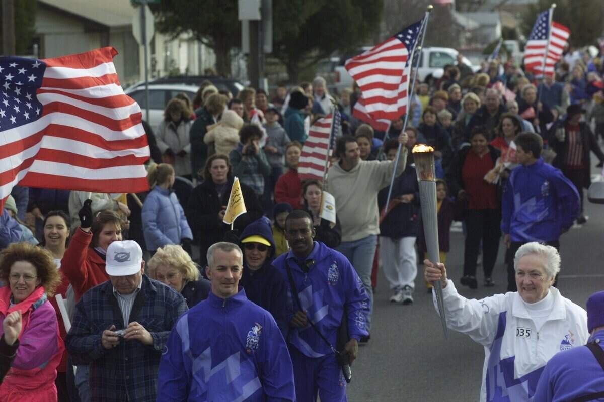Margaret Racy of Kennewick runs along Fourth Avenue in Kennewick, clutching the Olympic torch on Jan. 25, 2002.