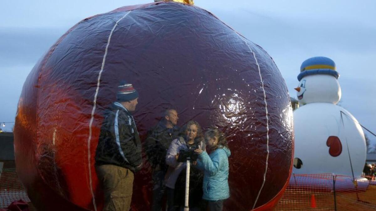 The Roy family, from right, McKenna, 10, Jamie, Jason and Mason, 6, of Kennewick, have their photo taken by AJ Taradis, left, in an inflatable ornament Saturday during the Winter Dreamland event at the Living Room Church in Kennewick. The family Christmas event featured the Snowzilla, a large winter slide, as well as a Christmas village, toy-making, an indoor snowball fight, and other attractions.