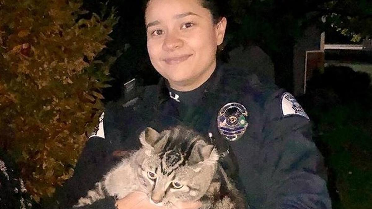 Pasco police Officer Ana Ramos holds Gilmore after rescuing the cat from a fenced garden. The owner’s face was blurred out by Pasco police.