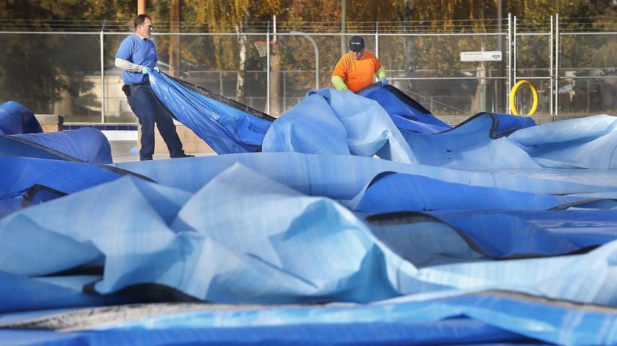 A pair of Pasco city employees wrangle some wrinkled up insulated pool covers Monday morning at Memorial Park after gusty weekend winds snarled them. The floating sections didn’t appear damaged but were tough to manhandle because of the added weight from water filling the wrinkled pockets. The pool is still in use by high school swimming programs.