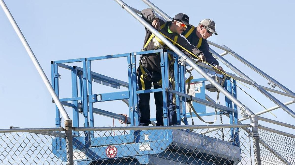Frontier Fence employees Leo Delgado, left, and Jerome Clifton measure twice and cut only once Thursday afternoon while working on the chain link backstop at the baseball field at Park Middle School in Kennewick.