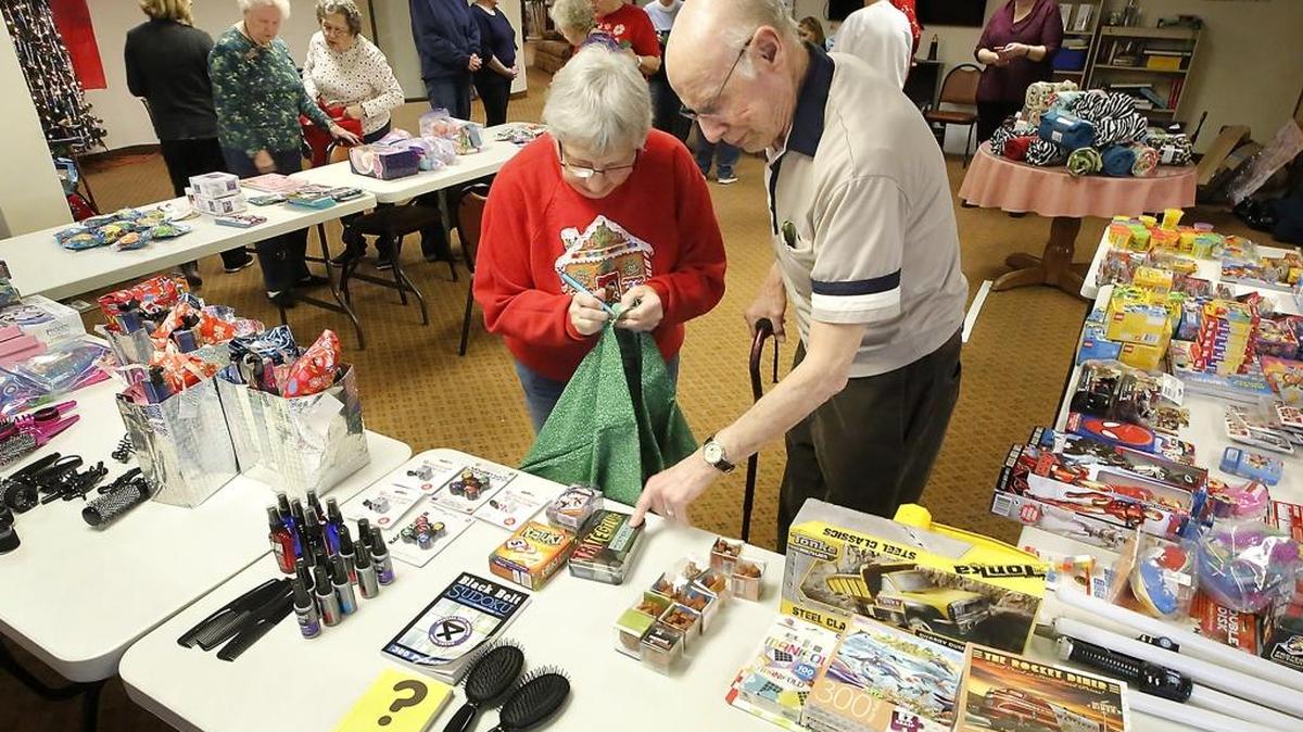 Embroidery club member Susan Peterson, left, and Bruce Cornelly, a resident at Solstice Senior Living in Kennewick, team up Wednesday to fill Santa bags with gifts for kids at the Tri-City Union Gospel Mission in Pasco. Volunteers filled about 40 personalized bags to be placed outside the doors of the sleeping areas when the kids go to bed Christmas Eve. Watch a video at tricityherald.com/video