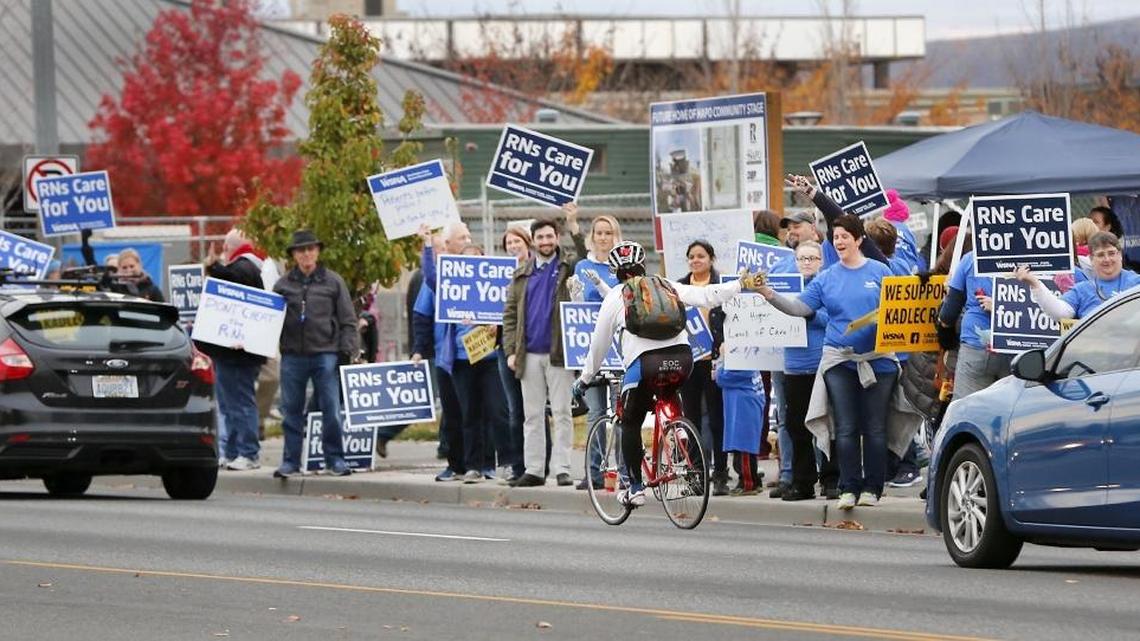 A bicyclist gives high-fives to Kadlec Regional Medical Center nurses gathered along George Washington Way at John Dam Plaza for a union rally Nov. 9.