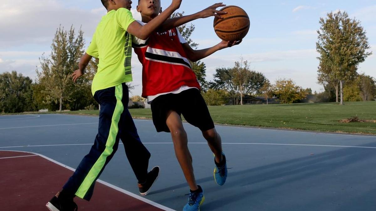 Kameron Cruz, right, 13, of Kennewick, is guarded by his brother Micah, 12, as he lines up a shot while playing basketball Friday afternoon at Highlands Grange Park in Kennewick. Rain showers are expected Saturday and Sunday around the Mid-Columbia, according to the National Weather Service.