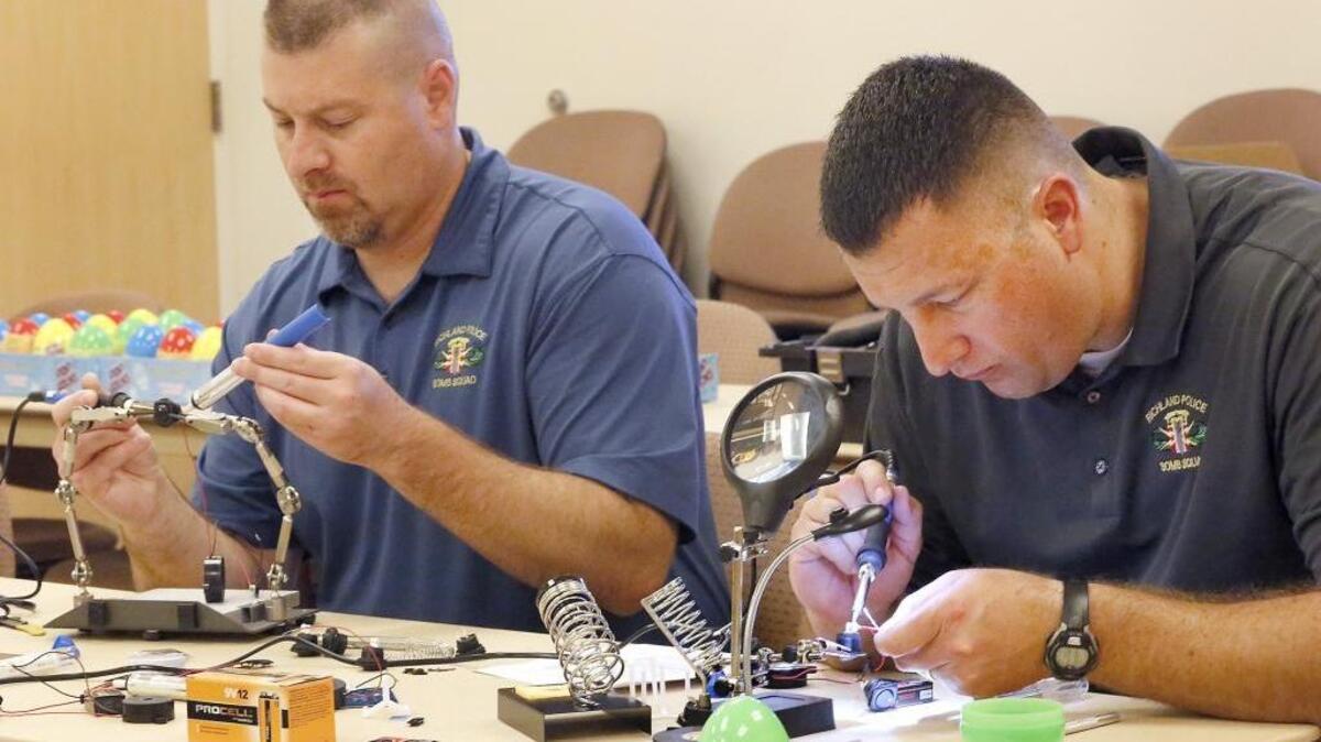 Richland police officers Alex Hesla, left, and Jason Crouch use soldering equipment Thursday to assemble electronic beeping Easter eggs for the Edith Bishel Center for the Blind and Visually Impaired. Bomb squad members volunteered to help the Kennewick agency prepare for next year’s Easter egg hunt for blind and visually impaired children by building the 48 battery-powered noise-emitting devices. Watch a video at tricityherald.com/video