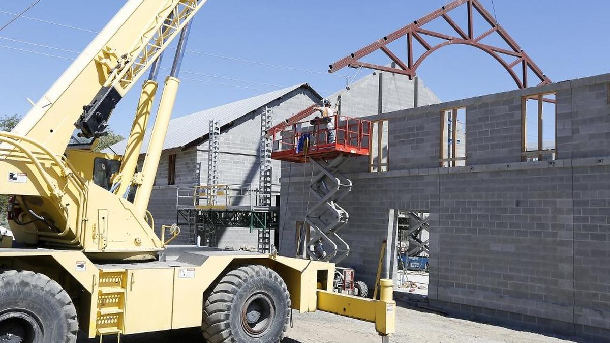 A worker helps guide a metal roof truss into place at the Port of Kennewick’s Columbia Gardens Wine and Artisan Village on east Columbia Drive in Kennewick. Construction is about 30 days behind schedule because of harsh winter weather in January and February.