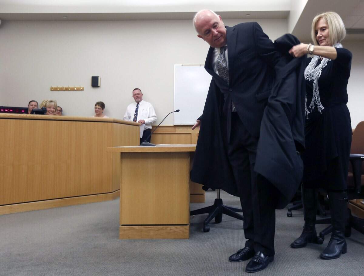 Steve Osborne puts on his new robes with help from wife Karen as he was sworn in as a Benton County District Court judge.