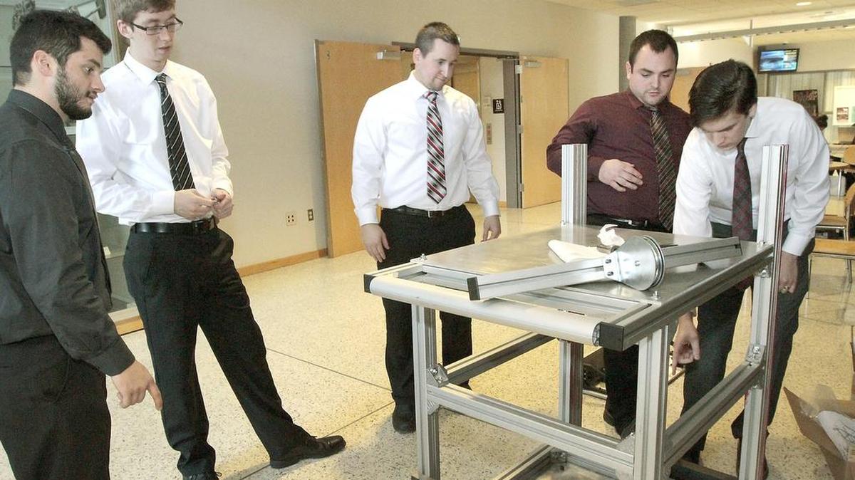 A team of WSU mechanical engineering students ponder improvements to their prototype that will compare 3D images of a nuclear material container to detect tampering. Two teams from Pullman participated with mentors from the Pacific Northwest National Laboratory in Richland and delivered their projects Friday to the Richland WSU campus. From left, they are: Sam Heyd, Kent Evans, Dylan Delay, Conner Huck and Tyas Young.