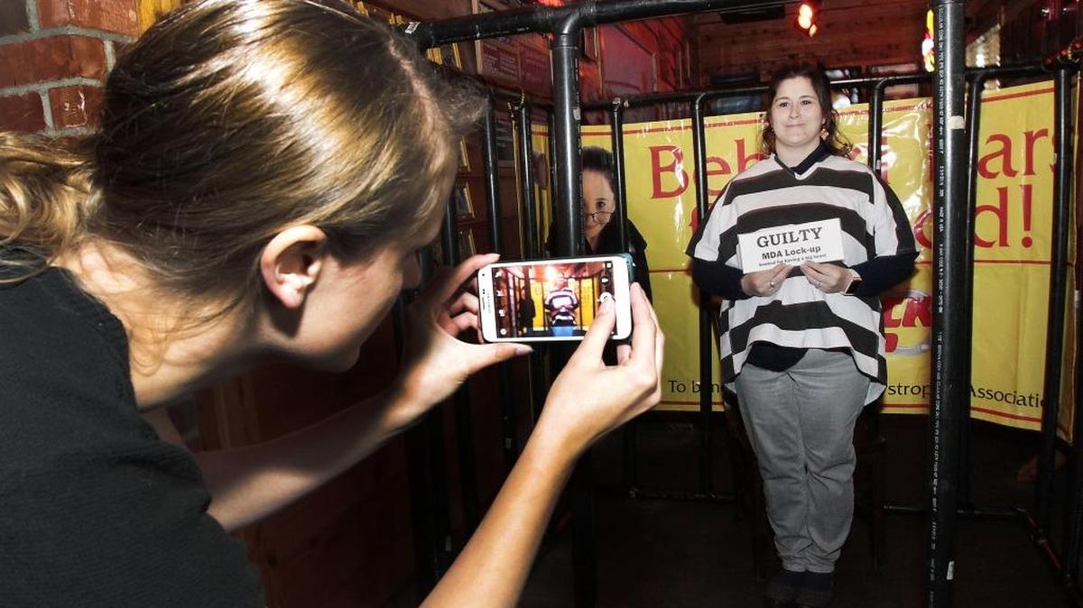 Tish Wilcox of Sheeps Clothing in Kennewick poses for her "booking mug" Thursday afternoon after being delivered to the Muscular Dystrophy Association's Lock-Up event at the Texas Roadhouse restaurant in Kennewick. About 60 community and business leaders participated in the annual fundraiser. The “jailbirds” used their hourlong sentence to raise “bail” by calling or emailing friends, family and coworkers for donations that benefit Tri-City families.