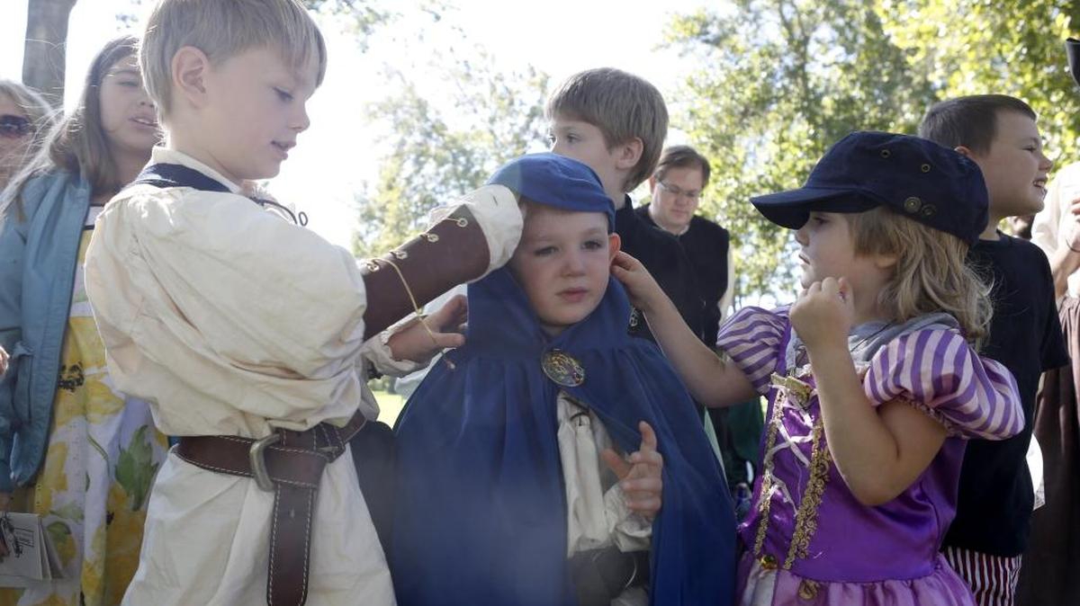 Thomas Rawlins, 6, left, and Sara Rawlins, 5, right, help their cousin Adam Rawlins, 5, put on the hood of his cape Saturday as they watch a jousting tournament at Ye Merry Greenwood in Columbia Park. The renaissance faire continues Sunday from 10 a.m. to 5 p.m. See a video at tricityherald.com/video