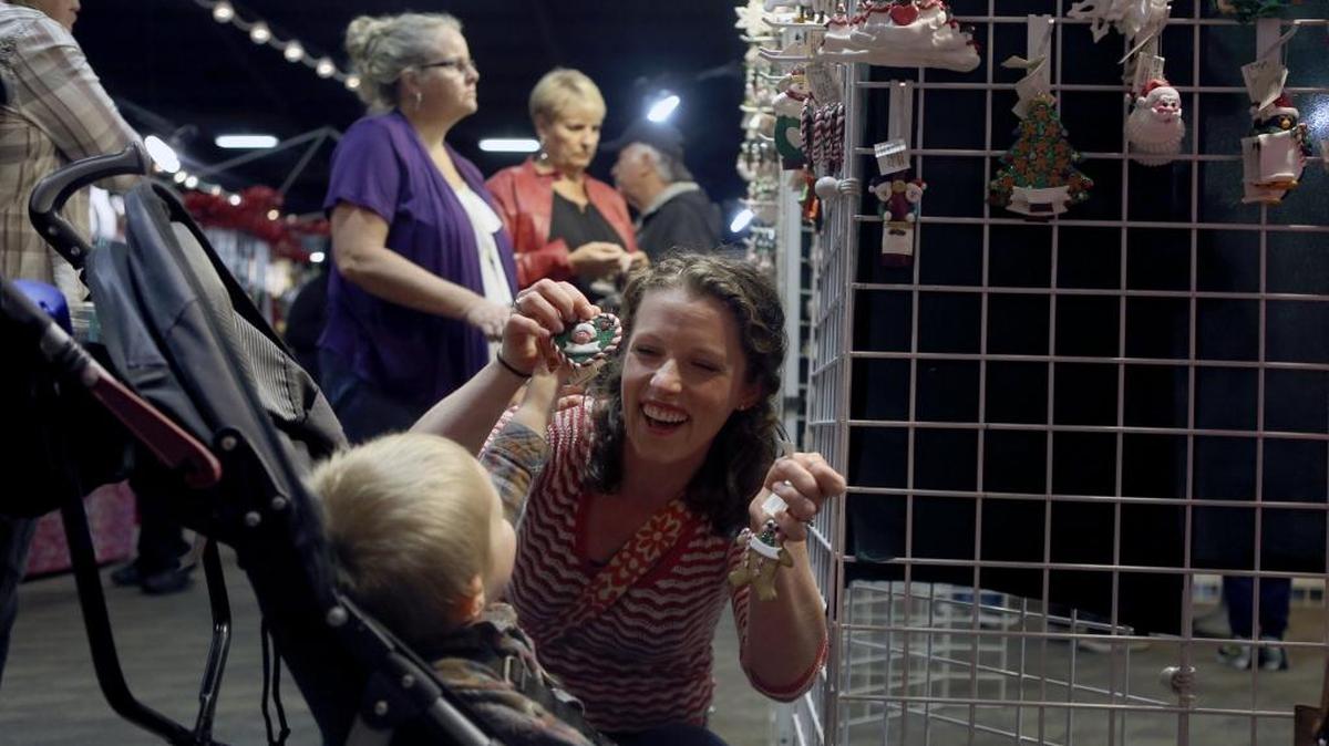 Ashley Daniels, of Benton City, gets some help from her son Gus, 2, as she picks out Christmas ornaments Friday at Jo’s Holiday Designs during the Custer’s Arts & Crafts Show at the TRAC Center in Pasco. The show, featuring over 150 professional artists and crafters, continues Saturday from 9 a.m. to 6 p.m. and Sunday from 10 a.m. to 4 p.m.