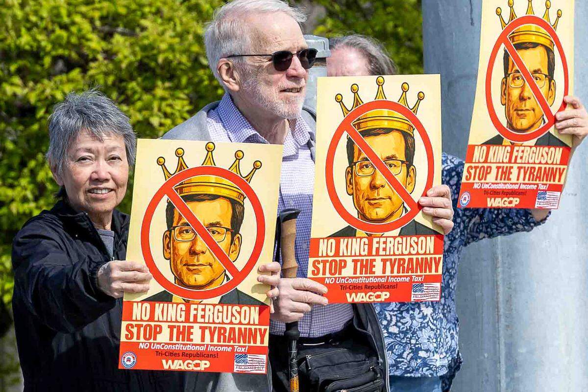 A couple dozen demonstrators protest Gov. Bob Ferguson and the Democrats’ proposed millionaires tax on Saturday in Richland.