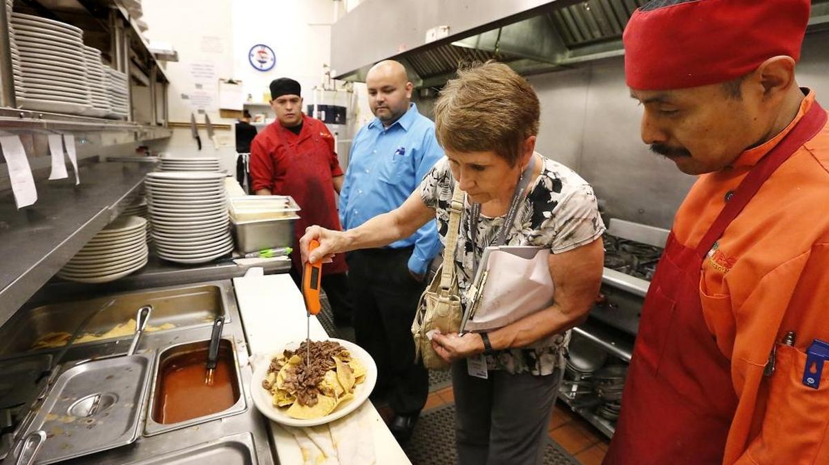 Judy Kitchen, with the Benton Franklin Health District food safety program, takes the temperature of a plate of nachos during a recent inspection of the Fiesta Mexican Restaurant on Gage Boulevard in Kennewick. Watching her are, from left, chef Samuel Gonzalez, manager Edgar Velazquez and chef Francisco Lozada. Kitchen complimented the two chefs on their teamwork in handling and cooking food to minimize cross-contamination and glove use.