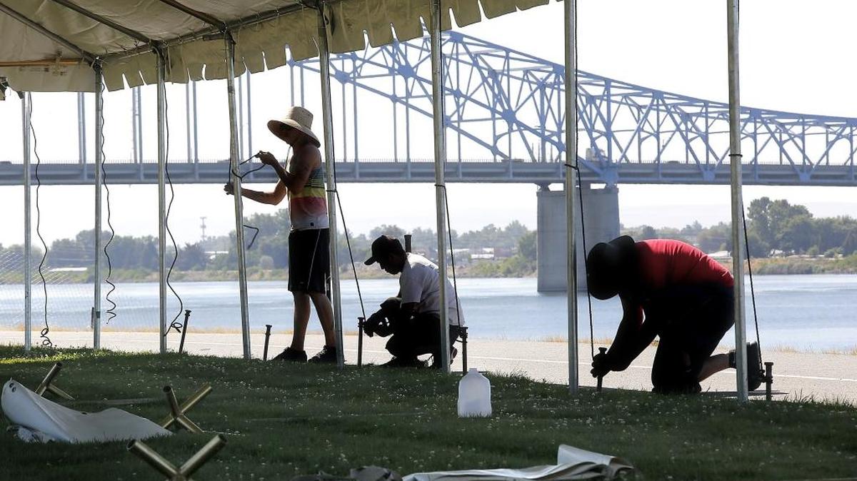Workers from Interstate Special Events are silhouetted against the Columbia River and the blue bridge on Tuesday as they tie down a huge tent in Pasco. The Portland, Ore.-company is setting up 118 tents, 550 tables and 4,200 folding chairs on both sides of the river for fans attending the three-day Tri-Cities Water Follies event. Friday is the first day of action. Follow all the hydroplane and air show action at www.tricityherald.com or follow us on Facebook and Twitter #TCHydros.